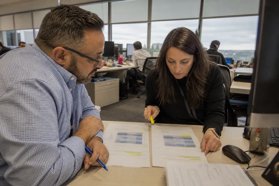 Head of reconciliations and an operations analyst comparing two vendor proposals side by side at a desk