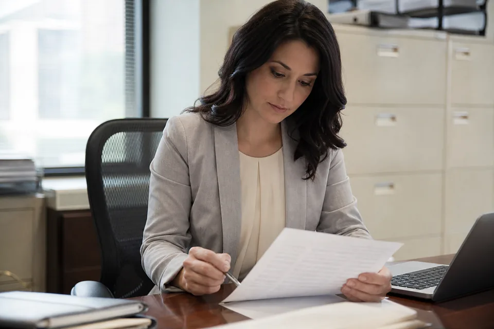 Deposit operations manager reviewing a printed list of outstanding cashier's checks