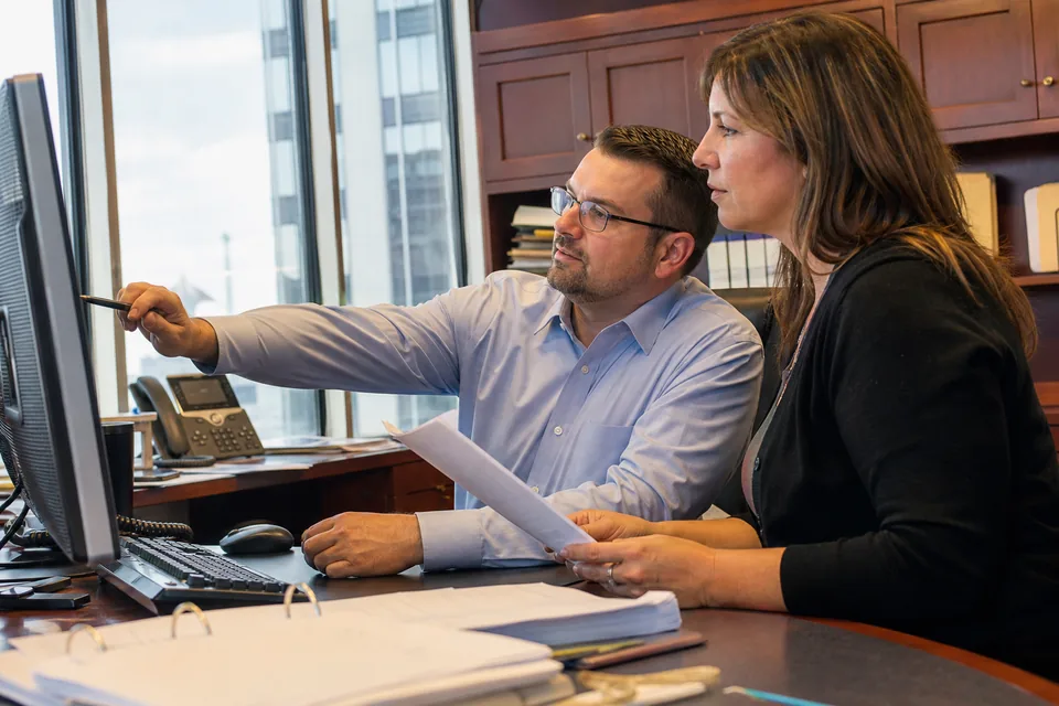 Treasury analyst and controller at a bank reviewing a prefunded instant payment position on a shared screen