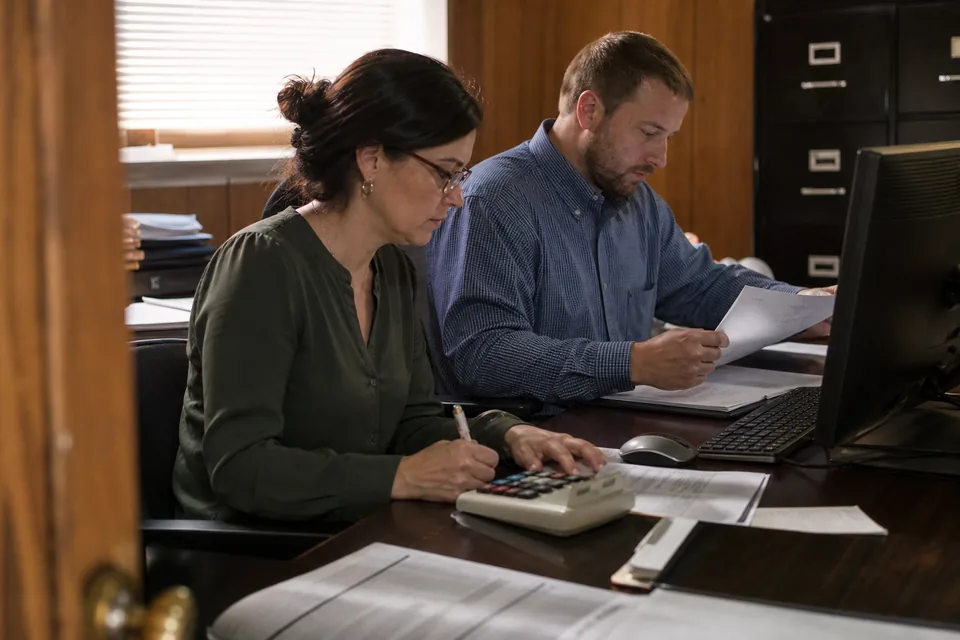 Credit union accounting manager and a staff accountant going through settlement account balances at a desk