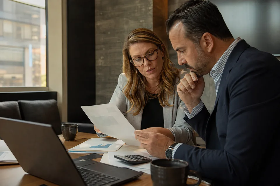Sponsor bank payments lead and a finance partner reviewing a usage based software quote at a conference table