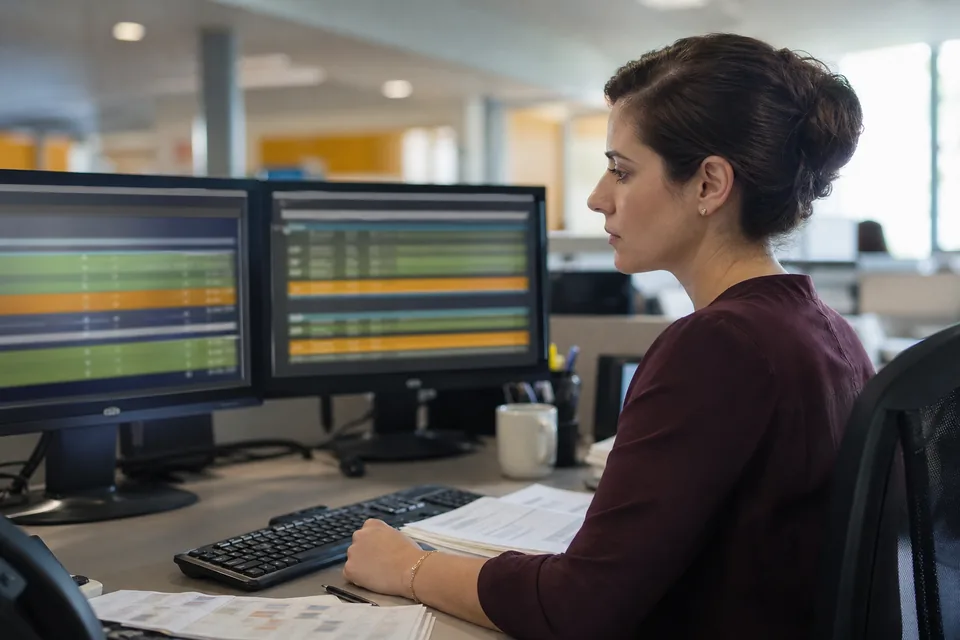 Bank operations analyst reviewing matched and unmatched transactions on two monitors